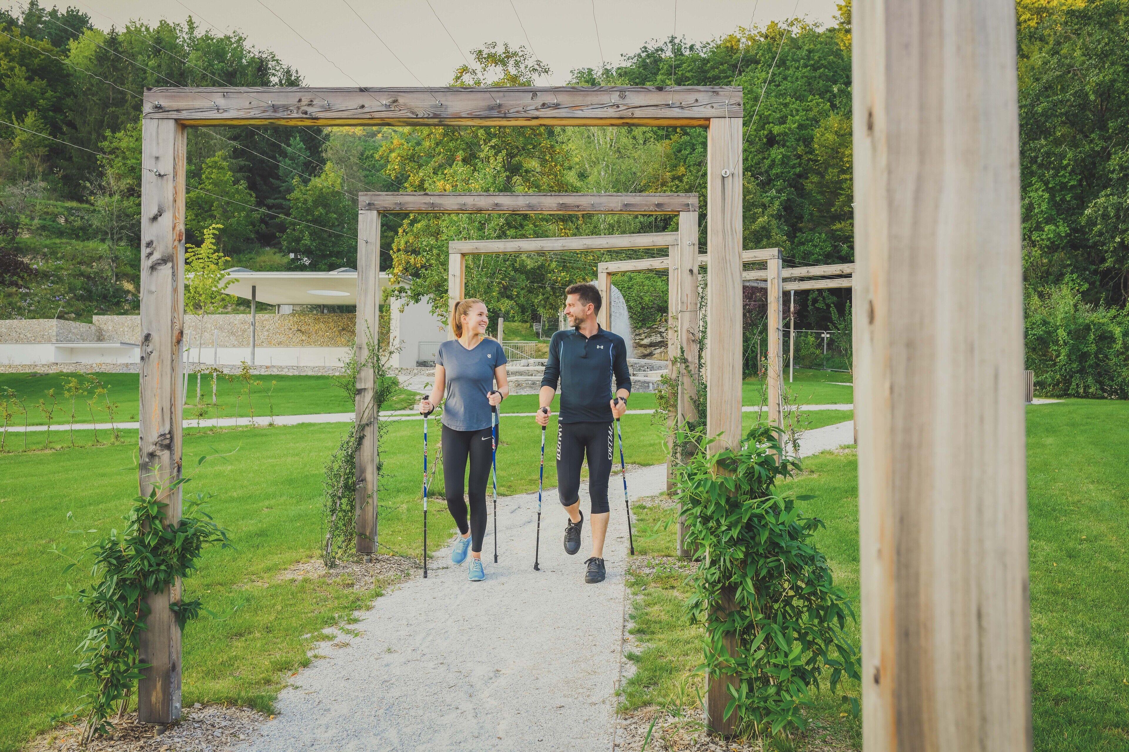 Eine Hollerne pergola in einem Park mit einem Kiesweg.