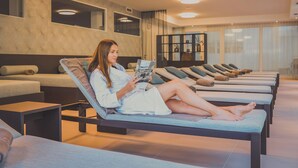 Een spa-ruimte met comfortabele loungestoelen, een massagetafel en een massagetafel met een massagestoel.