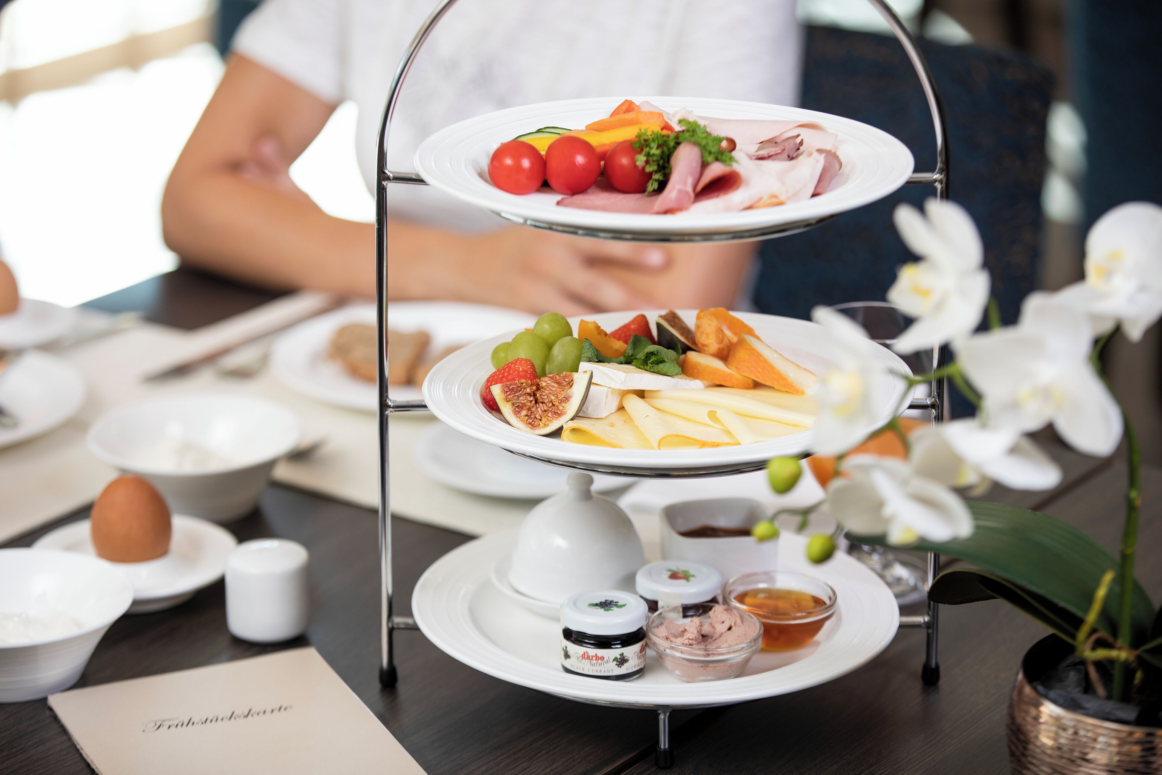 A three-tiered serving tray with various food items and condiments on a table.