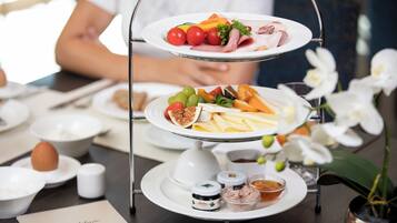 A three-tiered serving tray with various food items and condiments on a table.