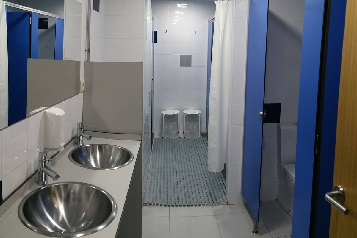 A modern bathroom with two sinks, a shower area, and a toilet.