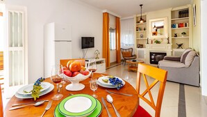 A dining area with a wooden table set for four, a television, and a bookshelf in the background.