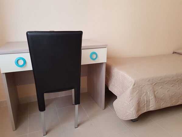 A bedroom with a bed, a desk, and a chair.