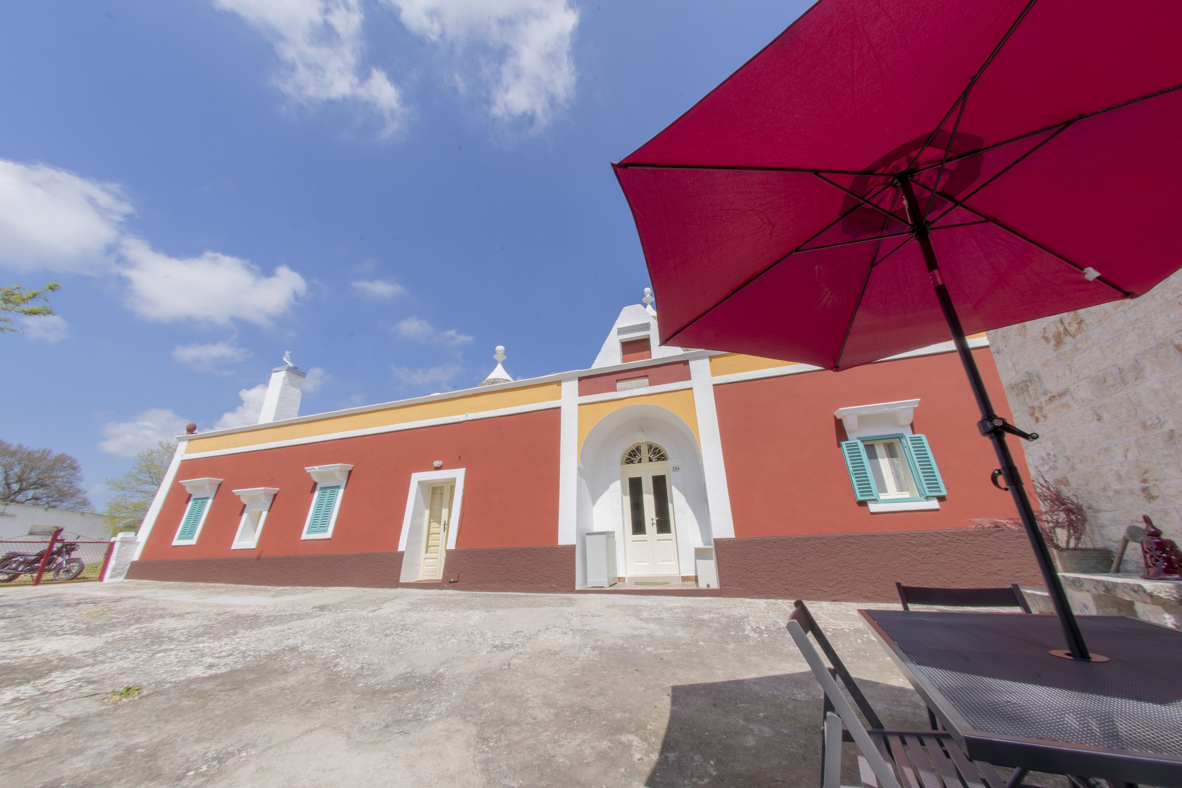 A building with a red facade, white door, and green shutters.