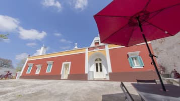 A building with a red facade, white door, and green shutters.