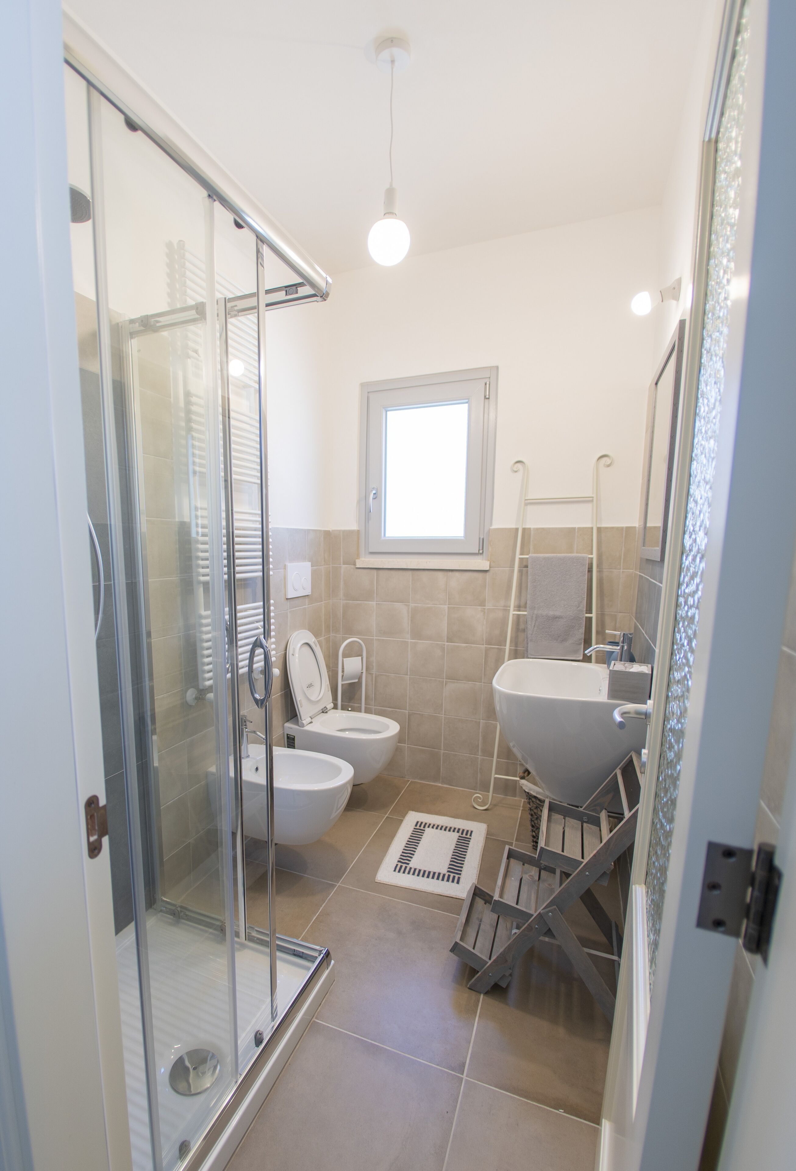 A bathroom with a glass shower enclosure, a toilet, a bidet, and a sink.