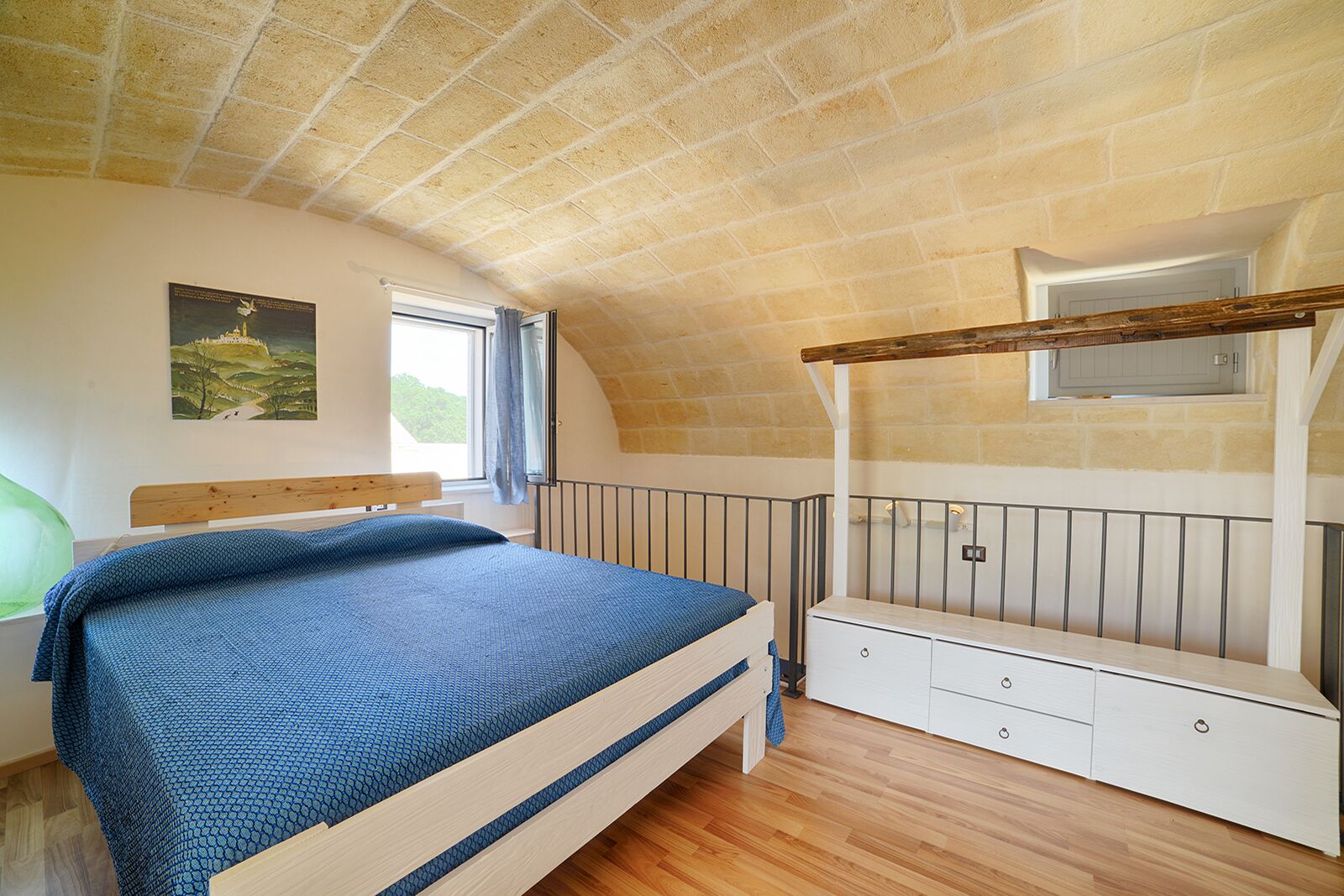 A bedroom with a wooden bed, a white dresser, a window with curtains, and a brick ceiling.