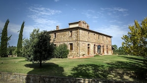 A stone building with a central courtyard, surrounded by trees and a clear sky.