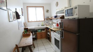 A compact kitchen with a sink, stove, microwave, and a dining table with chairs. - Charming farm with garden and BBQ in Bérigny (Bérigny)