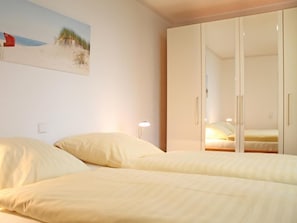 Ein Schlafzimmer mit zwei Betten, einem Kleiderschrank, einem Gemälde und einer Nachttischlampe.