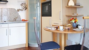 A compact kitchen with a microwave, a sink, and a dining area with chairs and a table. - Villa Seegarten Whg. Seg07 (Ostseebad Boltenhagen)