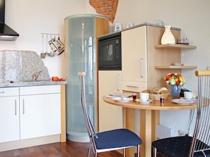 Une cuisine compacte équipée d’un four à micro-ondes, d’un évier et d’un coin repas avec des chaises et une table.