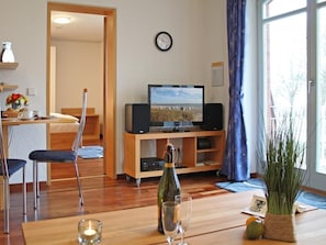 A living room with a television, a wooden table, a bottle, and a plant.