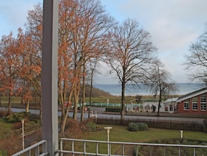 A view from a balcony overlooking a grassy area with trees and a building in the distance.