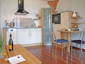 Een moderne keuken met een magnetron, koffiezetapparaat en een glazen kast.