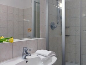 Une salle de bain avec un lavabo, un miroir et une douche.