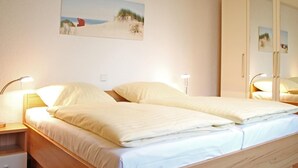 A double bed with a wooden headboard, two bedside tables with lamps, a painting on the wall, and a wardrobe with a mirror. - Villa Seegarten Whg. Seg07 (Ostseebad Boltenhagen)