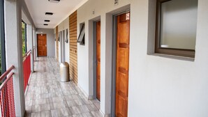 Un pasillo con puertas numeradas, un basurero y una ventana a la derecha.