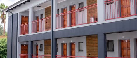 A multi-story hotel with balconies, wooden doors, and a grey facade.