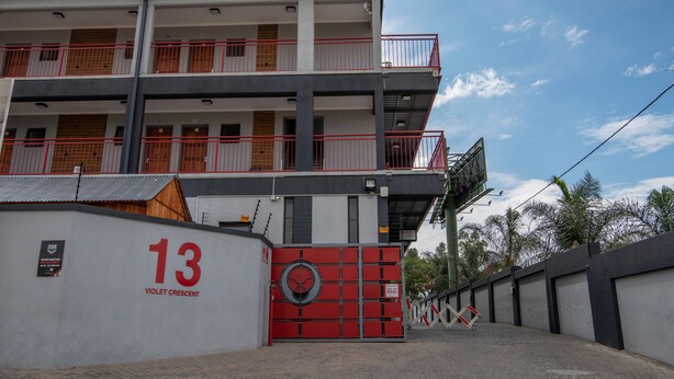 Un edificio de varios pisos con balcones, una verja roja y un letrero que indica el número 13.