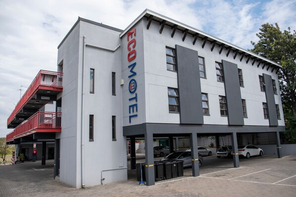A modern building with a sign reading "ECOMOTEL" and a parking area with several cars. - Ecomotel Marlboro (Sandton)