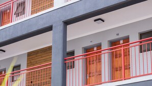Un aparcamiento de varios pisos con diseño moderno, que incluye una barandilla roja en el nivel superior y una zona cubierta con varios coches.