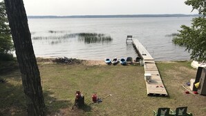 Une terrasse au bord du lac avec une jetée qui s’avance dans l’eau, comprenant un banc et plusieurs kayaks.