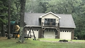 Une maison à deux étages avec un garage, un balcon et un arbre au premier plan.