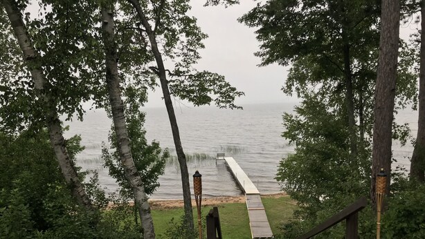Un escalier en bois menant à une jetée surplombant l’eau, entourée d’arbres.