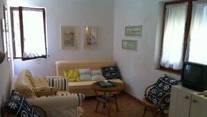 A cozy living room with a sofa, armchairs, a small table, and a television.