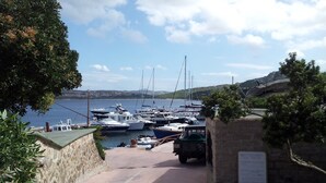 A marina with boats docked, a stone pathway leading to the water, and a signboard.