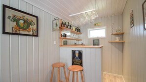A bar area with wooden stools, shelves with bottles, and a sign for 'TUBORG FADOL'. - 3 bedroom beautiful home in Ans By (Ans By)