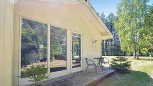 A covered patio with a wooden deck, a small table and chairs, and a potted plant. - 3 bedroom beautiful home in Ans By (Ans By)