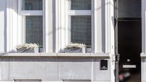 Fachada de edificio con dos ventanas y una puerta negra.