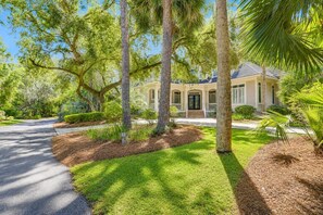 A house with a well-maintained lawn, trees, and a driveway.