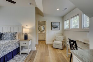 A bedroom with a bed, bedside table, lamp, chair, and a view of the bathroom.