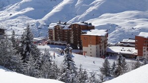 Ein verschneites Skigebiet mit mehrstöckigen Gebäuden, Skipisten und schneebedeckten Bäumen.