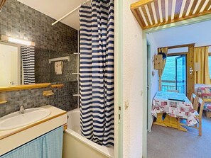 Un baño con bañera, lavamanos y cortina de ducha.