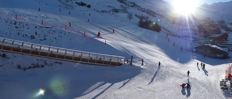 Una pista de esquí con telesilla, esquiadores y cielo despejado.