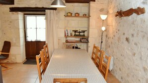 A dining room with a long table, wooden chairs, a chandelier, and a bookshelf with books and decorative items. - Charming 18th Century Gîte with Garden, Near Castles & Vineyards, Pet Friendly (Betz-le-Château)