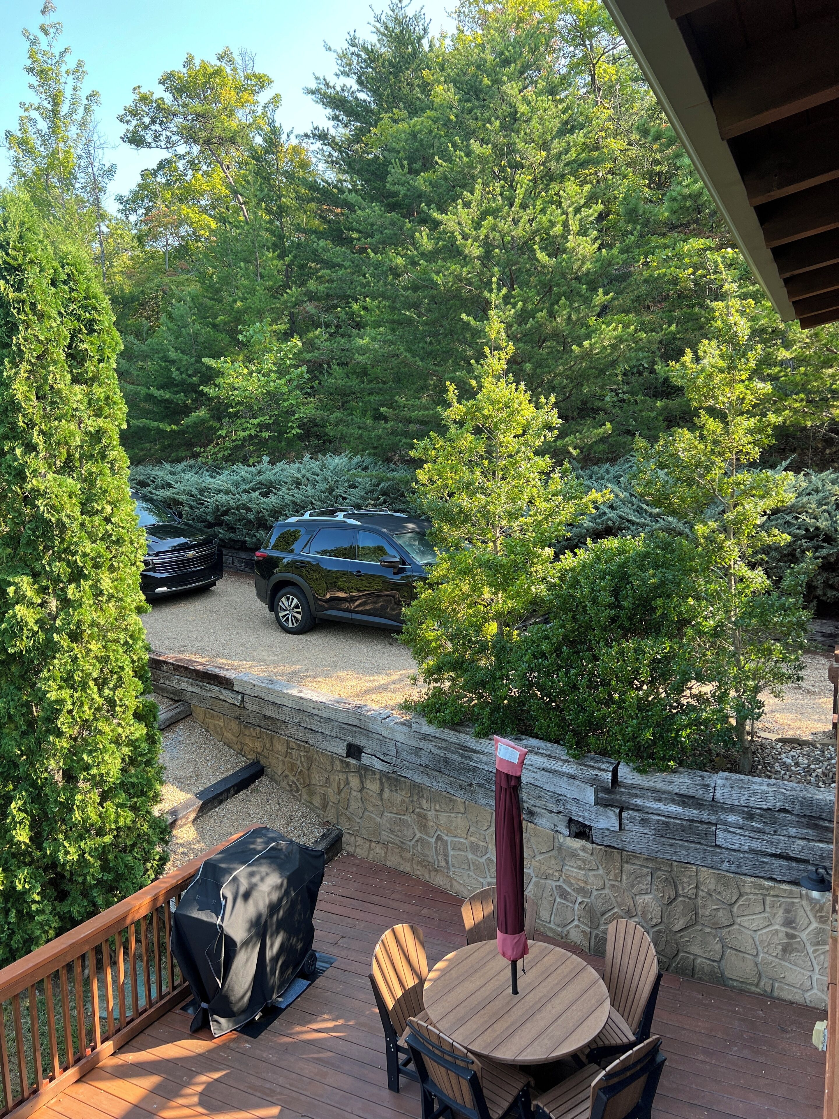A patio with a table and chairs, a barbecue grill, and a stone wall.