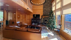 A spacious living room with a large brown leather sofa, a fireplace, and a Christmas tree.