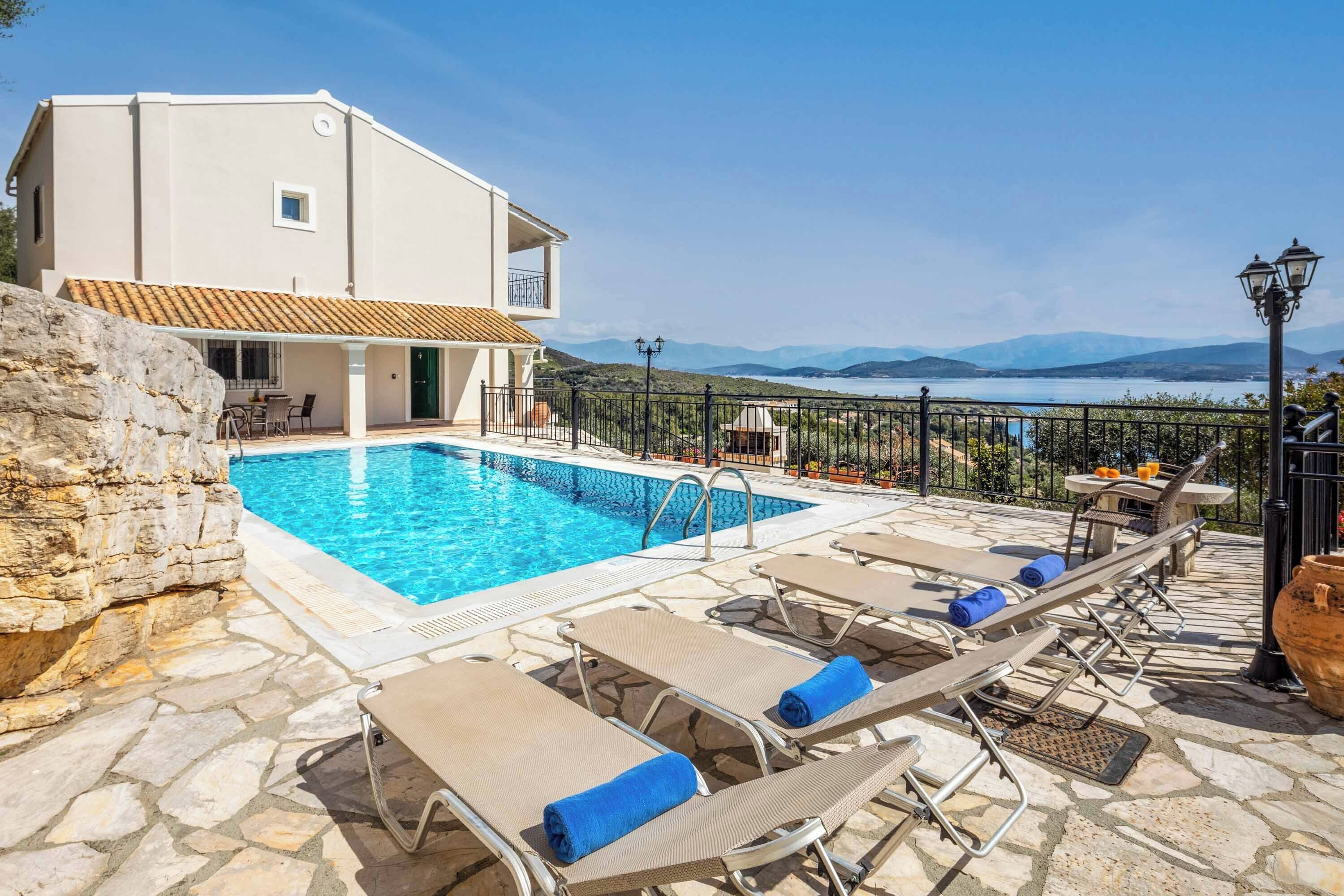 A pool area with lounge chairs and a view of the sea.