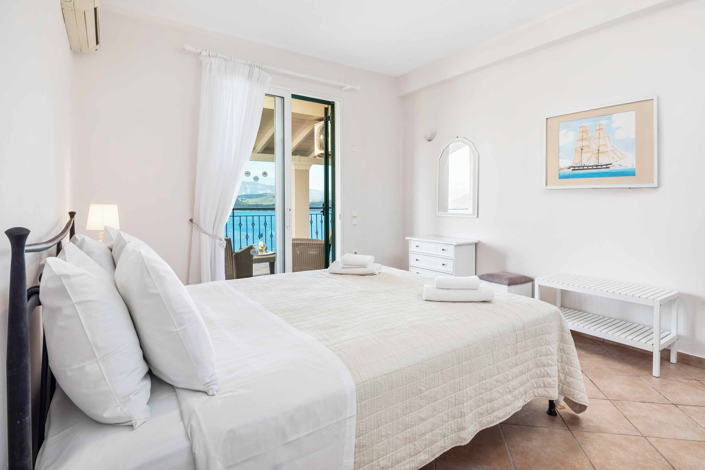 Un dormitorio con cama, cómoda, espejo y ventana con vista al mar.