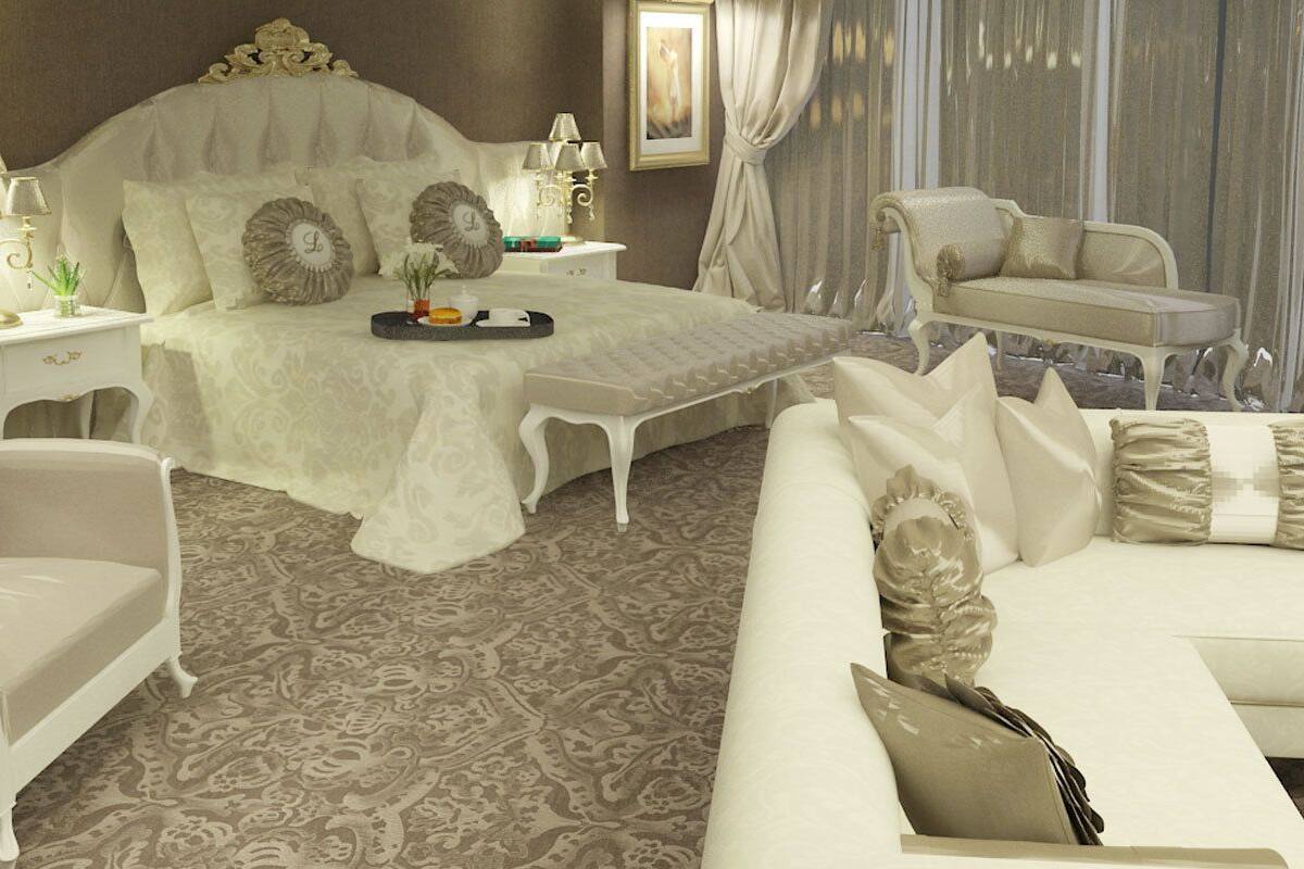 A bedroom with a large bed, a sitting area with a sofa, and a bedside table with lamps.