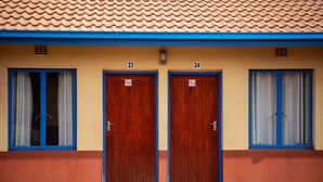 A building with two doors labeled 23 and 24, each with a window and a curtain. - Ecomotel Isando (Kempton Park)