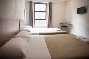 Habitación de hotel con dos camas, un escritorio, una silla, un televisor y una ventana con cortinas.