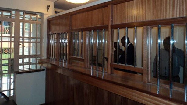 A hallway with wooden paneling and glass doors, leading to a room with a ceiling light fixture.
