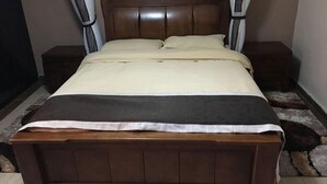 A wooden bed with a headboard, two bedside tables, and a blanket.