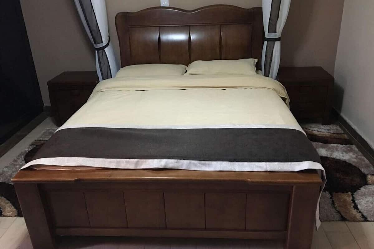 A wooden bed with a headboard, two bedside tables, and a blanket.